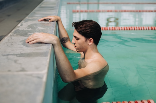 Instructor de natación masculino posando en la piscina