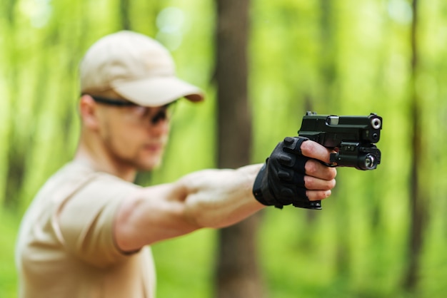 Instructor con pistola en bosque conduce apuntando y posando