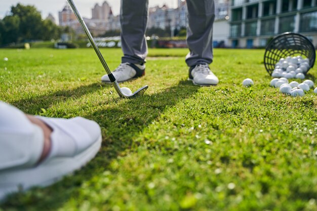 un instructor que enseña a su cliente a jugar al golf en el campo de prácticas