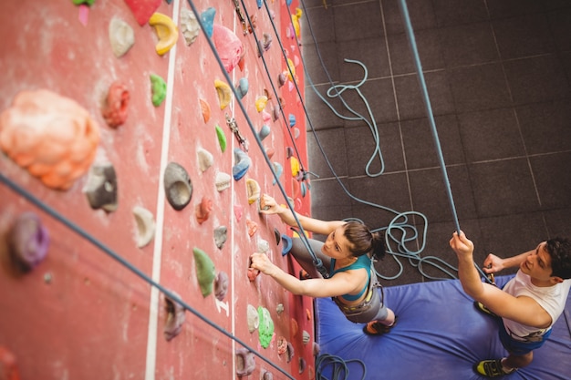 Instructor que orienta a mulher na parede de escalada