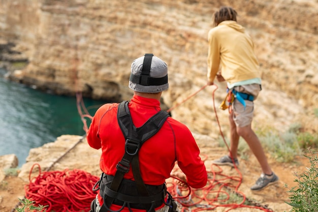 El instructor de salto del acantilado prepara el seguro y el equipo antes del salto Ropejumping