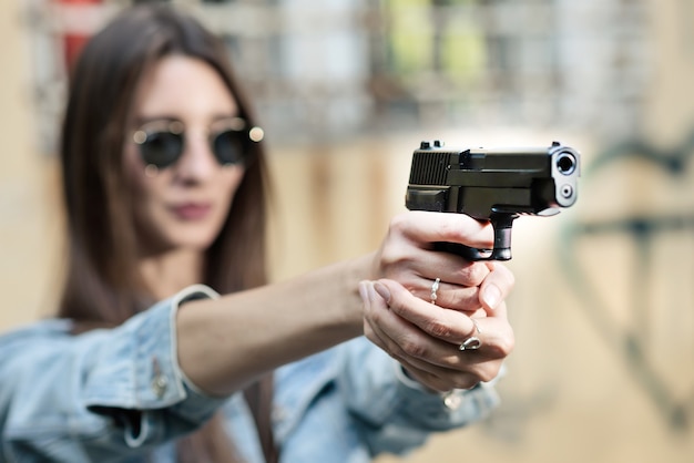 Instructor de tiro chica con una pistola en la mano apuntando al objetivo