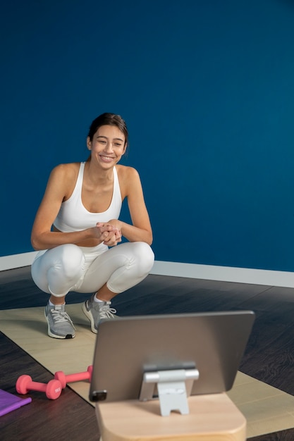 Foto instructora de fitness femenina enseñando una clase en casa con tablet