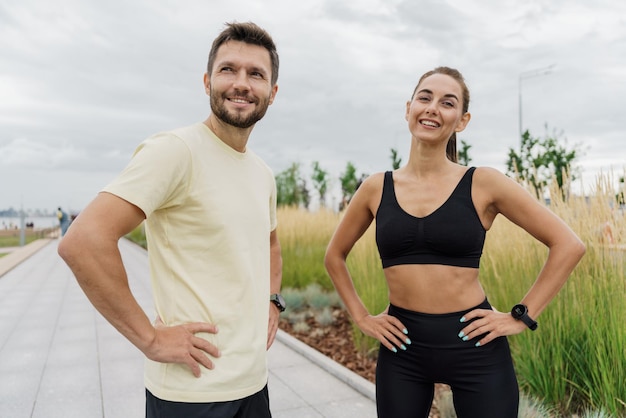 Los instructores de amigos usan un reloj de fitness y una aplicación deportiva. Personas fuertes y seguras en ropa deportiva.