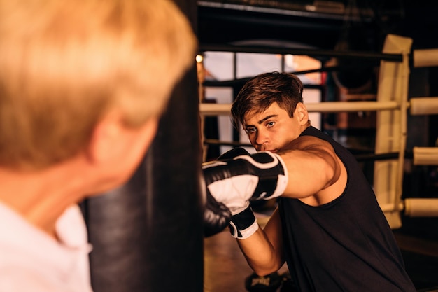 Instruktor steht neben dem Boxersack im Boxring