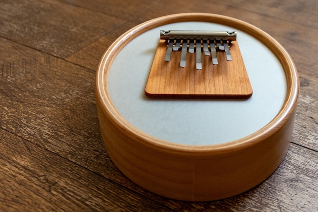 Instrumento de madeira sansula ou kalimba com membrana sobre um fundo de chão de madeira com espaço de cópia