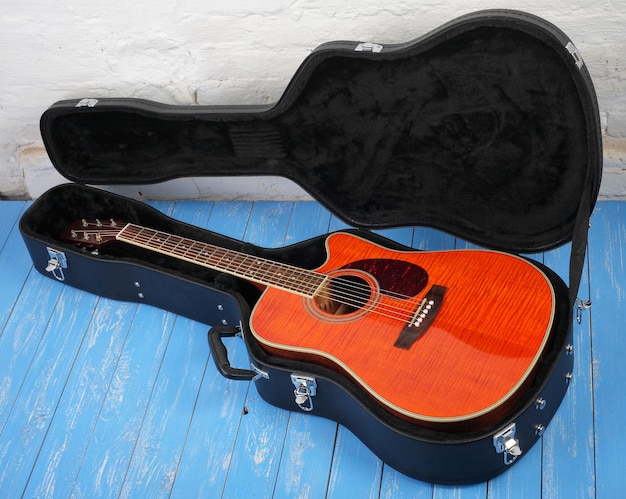 Foto instrumento musical guitarra acústica naranja en estuche rígido