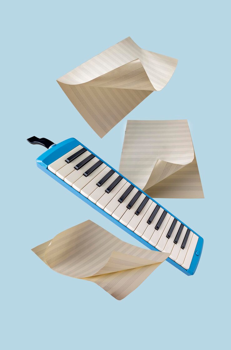 Foto instrumento musical melodika y hojas de papel para grabar notas vuelan sobre un fondo azul
