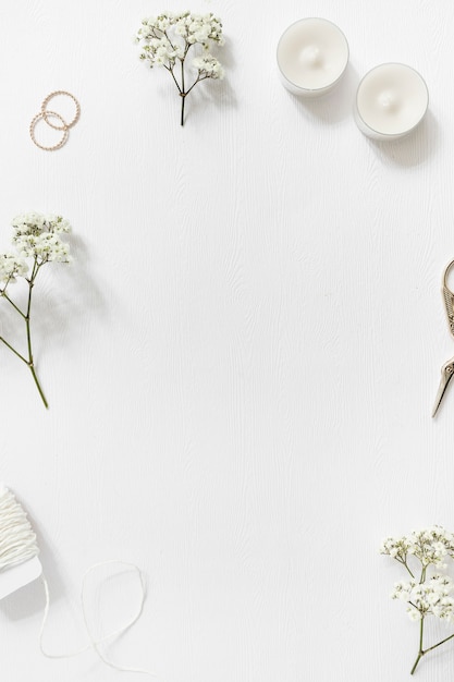 Foto instrumentos de cuerda; gypsophila; anillos de boda; velas y tijera sobre fondo blanco con copyspace para texto