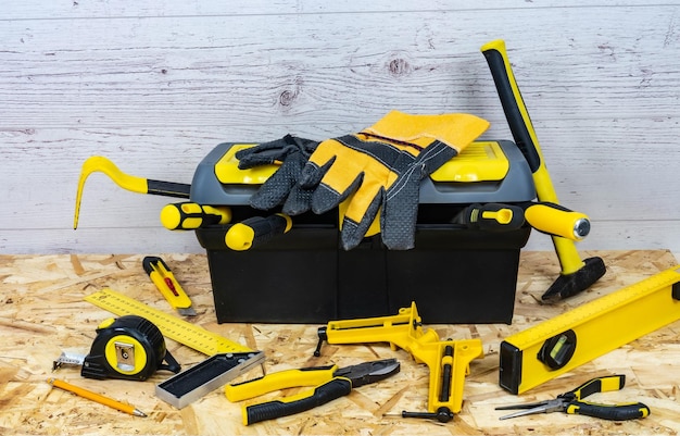 Instrumentos de construção amarelos e uma caixa de ferramentas em um fundo de madeira