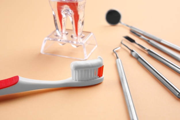 Instrumentos dentales de cepillo de dientes y maqueta de dientes de plástico sobre fondo de color