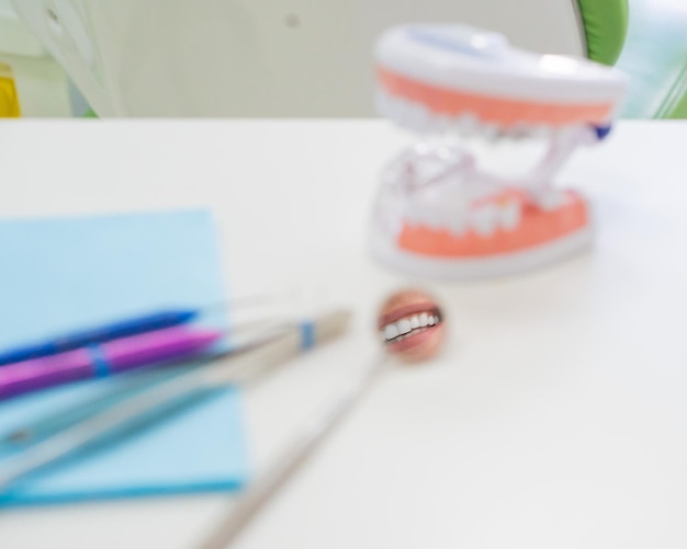 Los instrumentos estériles están en la oficina del dentista. Unas pinzas de espejo, una sonda y un diseño de mandíbula están en la mesa del ortodoncista. Examen de prevención de caries de higiene bucal.