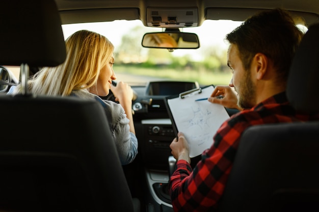 Instrutor ajuda mulher a dirigir o carro