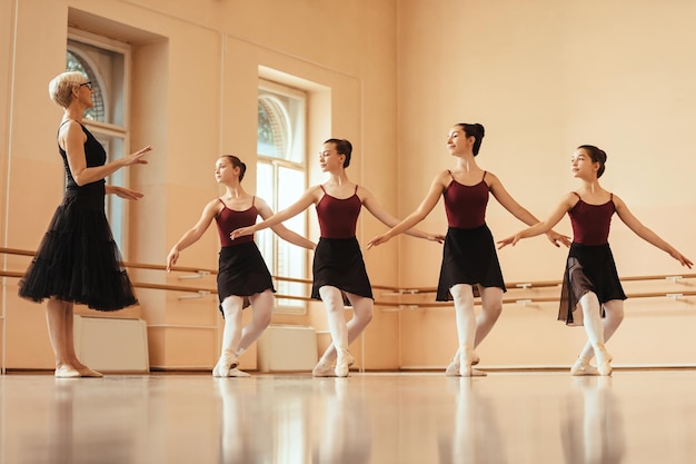 Foto instrutor de balé maduro ensinando grupo de bailarinas no estúdio de dança