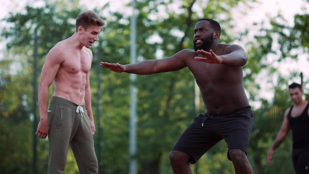 Instrutor de fitness masculino treinando homem afro-americano no playground esportivo ao ar livre