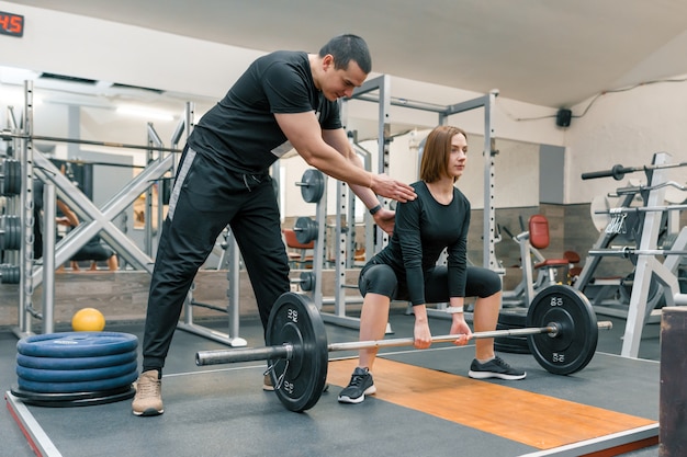 Instrutor de fitness pessoal masculino, ajudando a jovem a fazer exercícios