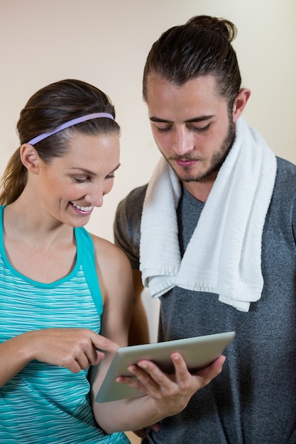 Instrutor de fitness sorridente e mulher usando tablet digital