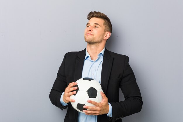 Instrutor de futebol jovem sorrindo confiante com braços cruzados.