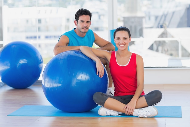 Instrutor e mulher sorridente com bola de exercício na academia