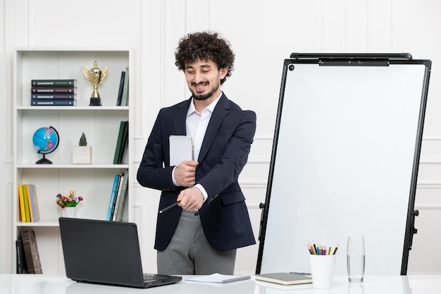 Instrutor moreno professor com computador de terno e quadro branco em sala de aula explicando uma palestra