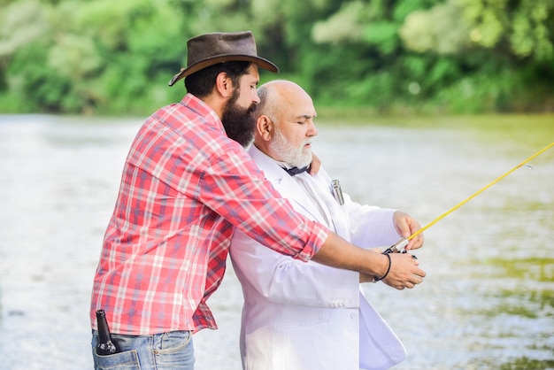Instrutor pessoal Homem barbudo e empresário elegante pescam juntos Aprenda a pescar Peixe com companheiro que pode oferecer ajuda em emergências Habilidades de pesca Homens amigos relaxando o fundo da natureza