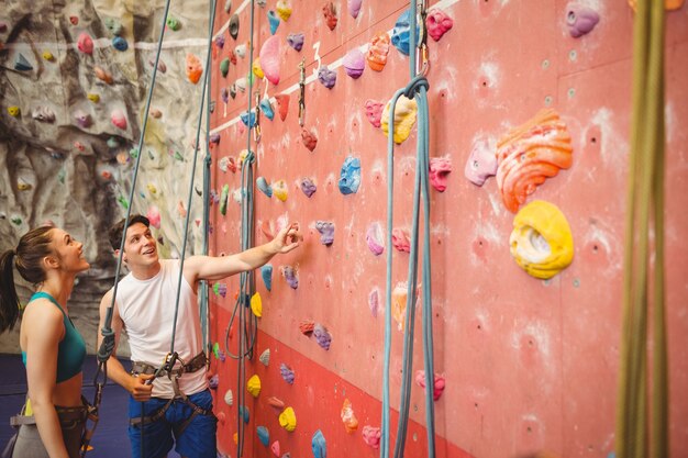 Instrutor que mostra a mulher parede de escalada