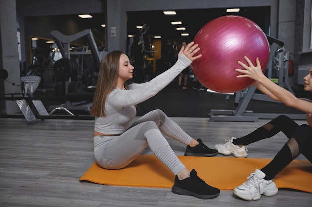 Instrutora de fitness se exercitando com seu cliente adolescente fazendo abdominais com bola em forma