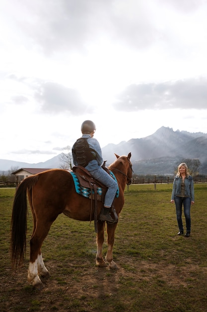 Instrutora equestre feminina ensinando criança a andar a cavalo