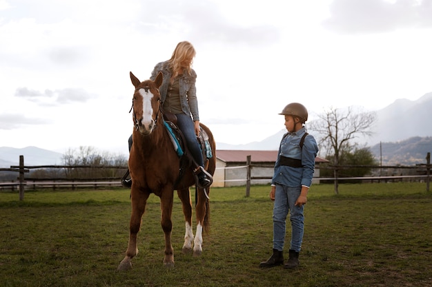Foto instrutora equestre feminina ensinando criança a andar a cavalo