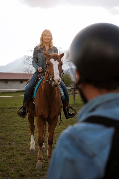 Foto instrutora equestre feminina ensinando criança a andar a cavalo