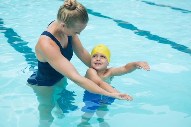 Instrutora treinando menino na piscina