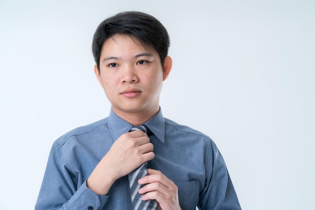 Inteligente atractivo empresario asiático mano conjunto corbata en camisa azul listo para trabajar