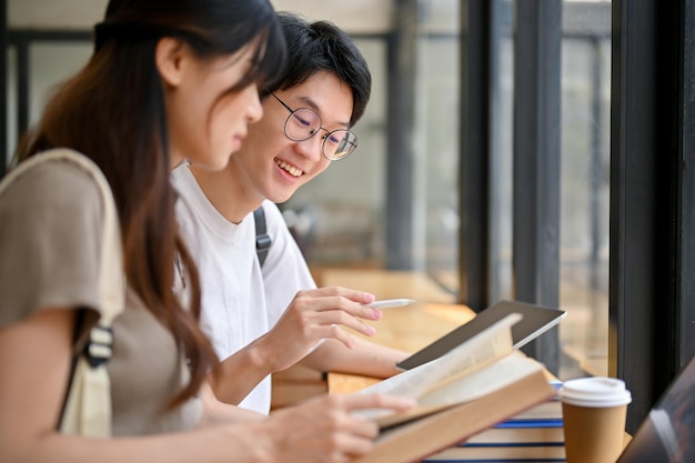 Inteligente jovem estudante universitário asiático ensinando história para sua namorada em um café