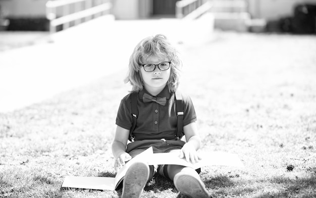 Inteligente nerd curioso em óculos lendo estudo de livro com gênio ao ar livre de caderno