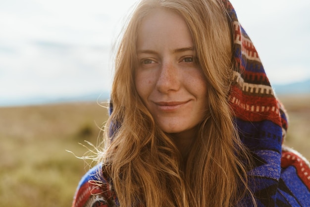 Inteligentemente, o rosto fabuloso de uma garota ruiva sem maquiagem com sardas no rosto e um meio sorriso gentil contra a estepe do deserto