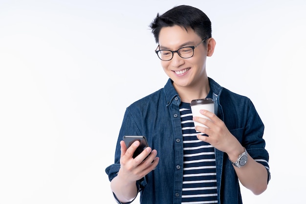 Intelligente attraktive asiatische Brille männliche Hand halten Heißgetränk Kaffee Handsuche und Blick auf den Smartphone-Bildschirm mit Frische und fröhlichem, lässigem weißem Hintergrund