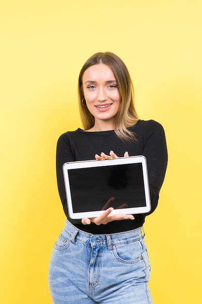 Intelligente, intelligente, kaukasische junge Studentin mit digitalem Tablet, isoliert auf gelbem Hintergrund