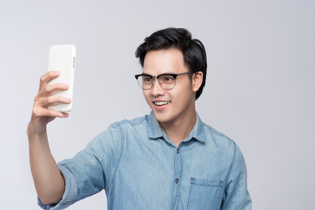 Intelligenter, lässiger asiatischer Mann, der ein Selfie-Foto mit dem Smartphone macht