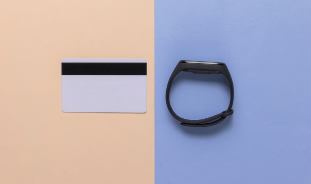 Intelligentes Armband und Bankkarte auf pastellfarbenem Hintergrund. Kontaktloses Bezahlen. Ansicht von oben. Minimalismus