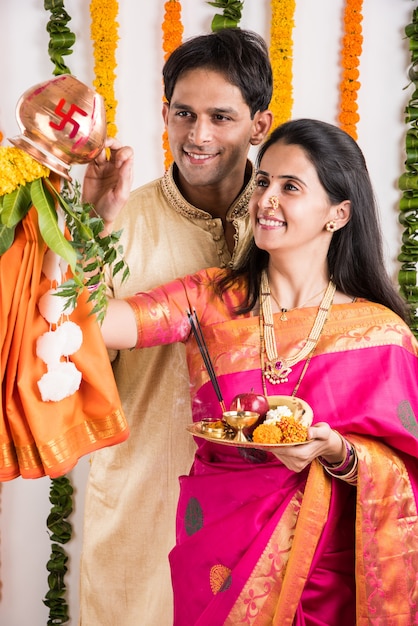 Intelligentes indisches junges Paar, das Gudi Padwa Puja in traditionellen Tüchern & Pooja Thali durchführt. Es ist ein hinduistisches Neujahr, das in ganz Indien gefeiert wird
