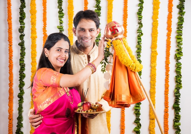 Intelligentes indisches junges Paar, das Gudi Padwa Puja in traditionellen Tüchern & Pooja Thali durchführt. Es ist ein hinduistisches Neujahr, das in ganz Indien gefeiert wird