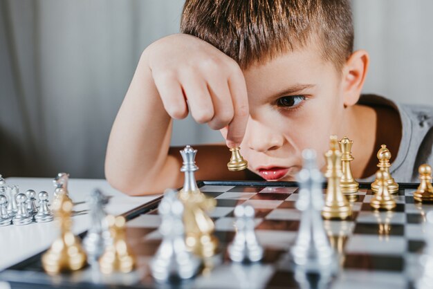 Intelligentes Kind, das zu Hause Schach in seinem Zimmer spielt