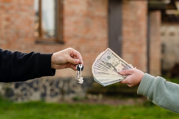 Intercambio de dinero en efectivo y llave de casa frente a una casa Compra o alquiler de bienes inmuebles Seguro hipotecario