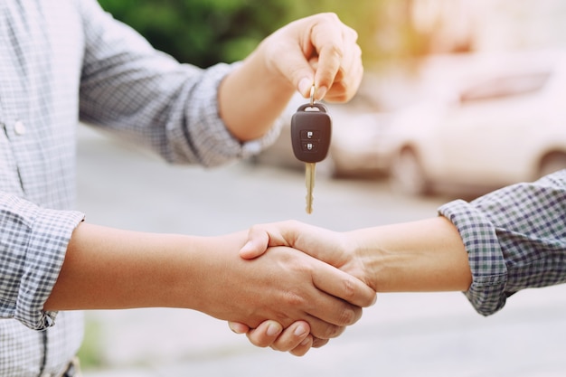 Intercambio de empresario entregando las llaves del coche a una mujer joven.