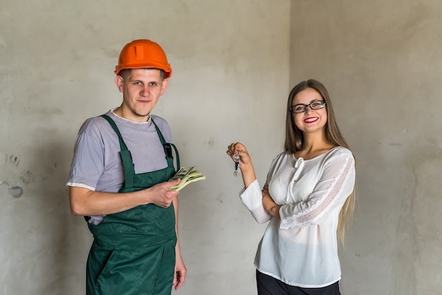 Intercâmbio entre homem construtor com chaves e mulher com dinheiro