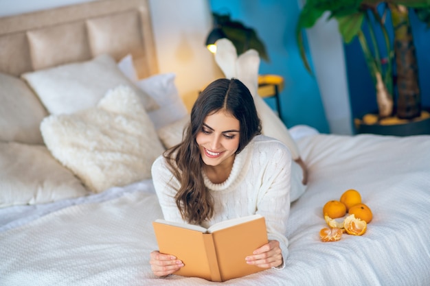 Interessado. Bela jovem lendo um livro e parecendo pensativa