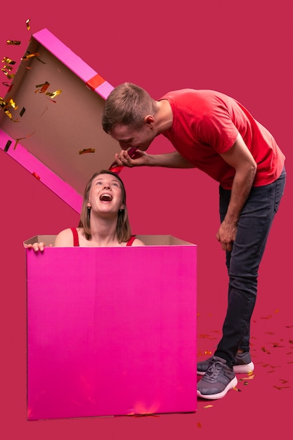 Foto interessantes foto von einem freund, der eine große rosa geschenkbox öffnet und darin seine freundin sieht ...