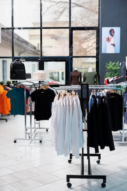 Interieur einer modischen Boutique mit Kleidern auf Kleiderbügeln, stilvollem Markendesign und formeller Kleidung im modernen Ausstellungsraum. Leeres Bekleidungsgeschäft im Einkaufszentrum mit trendigen Waren, kommerzielle Aktivität.