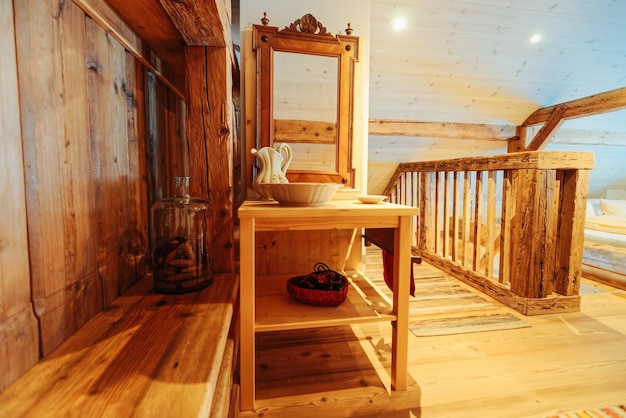 Interieur im Schlafzimmer mit Spiegel, Holztisch und Keramikgeschirr. Gestaltung des Dachbodens. Holzmöbel des Zimmers. Wohnkultur. Haus Wohnung. Gemütlicher Stil. Rustikal, Vintage und Handarbeit.