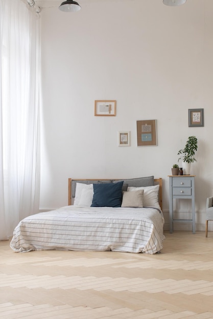 Interior del acogedor dormitorio blanco y gris con plantas en la mesita de noche